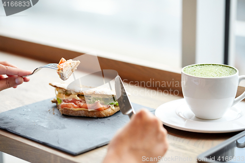 Image of woman eating salmon panini sandwich at restaurant