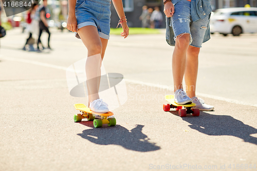 Image of teenage couple riding skateboards on city street