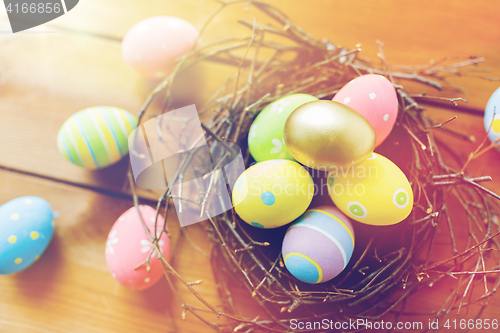 Image of close up of colored easter eggs in nest on wood