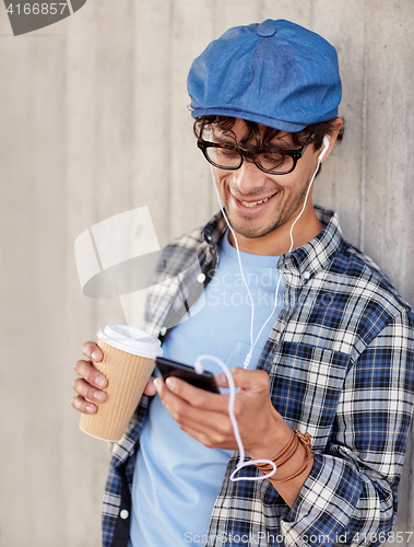 Image of man with earphones and smartphone drinking coffee