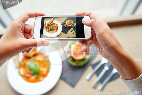 Image of hands with smartphone photographing food