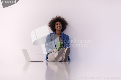 Image of african american woman sitting on floor with laptop