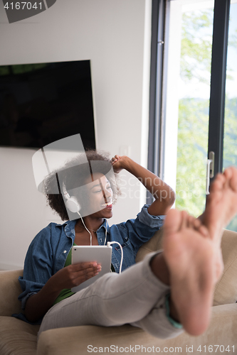 Image of African american woman at home in chair with tablet and head pho