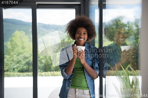 Image of African American woman drinking coffee looking out the window