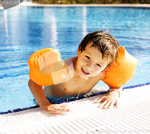 Image of little cute boy in swimming pool wearing handcarves