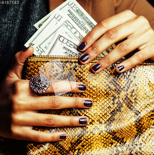 Image of pretty fingers of african american woman holding money close up with purse, luxury jewellery on python clutch, cash for gifts