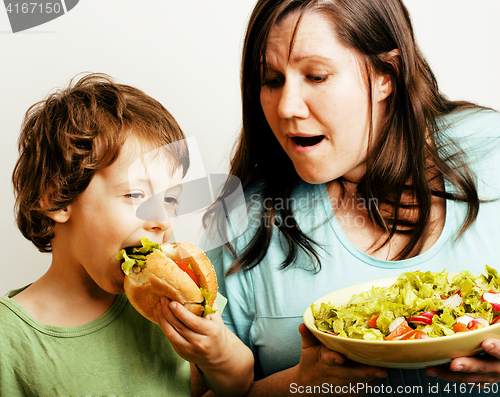 Image of fat woman holding salad and little cute boy with hamburger teasing