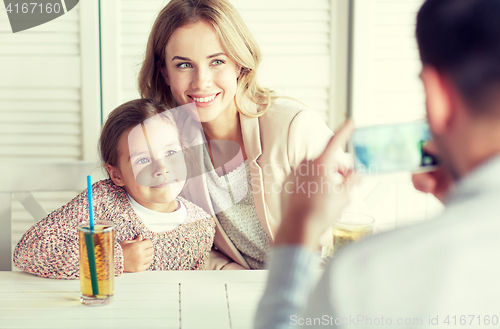 Image of happy family picturing by smartphone at restaurant