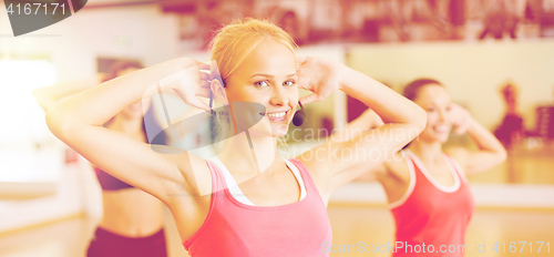 Image of group of smiling people exercising in the gym