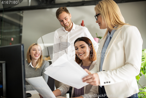 Image of happy creative team with papers in office