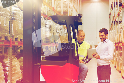 Image of men with tablet pc and forklift at warehouse