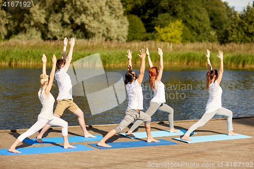 Image of group of people making yoga exercises outdoors