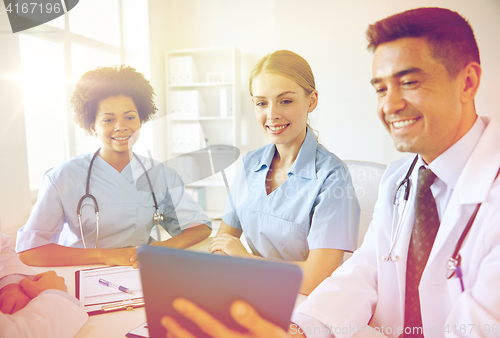 Image of happy doctors with tablet pc meeting at hospital