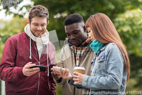 Image of happy friends with smartphone and coffee outdoors