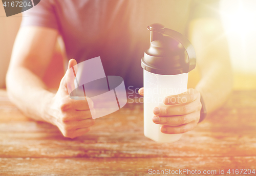 Image of man with protein shake bottle showing thumbs up