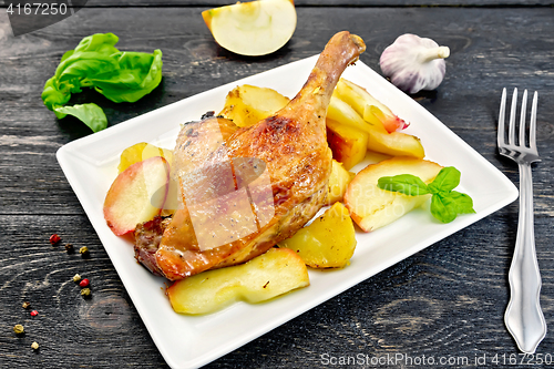 Image of Duck leg with apple and basil in plate on board