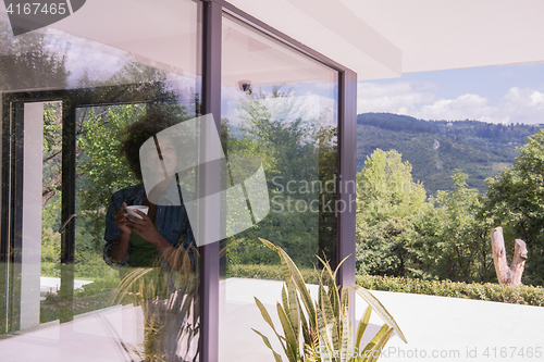 Image of African American woman drinking coffee looking out the window