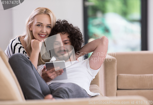 Image of couple relaxing at  home with tablet computers