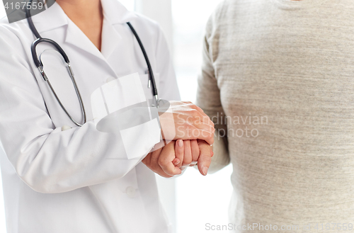 Image of close up of doctor holding old man hand