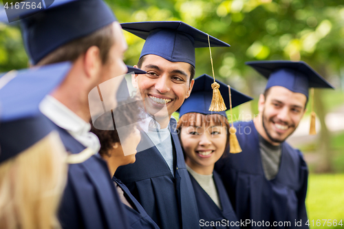 Image of happy students or bachelors in mortar boards