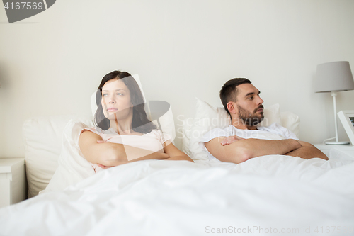 Image of unhappy couple having conflict in bed at home