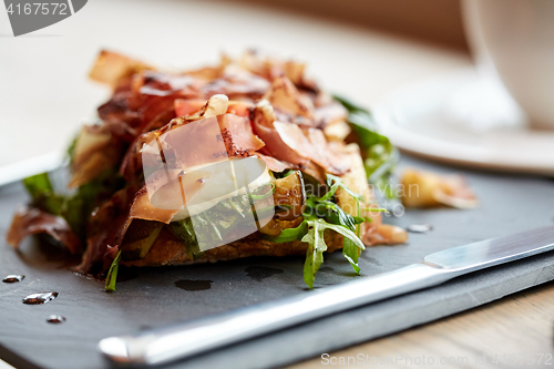 Image of prosciutto ham salad on stone plate at restaurant