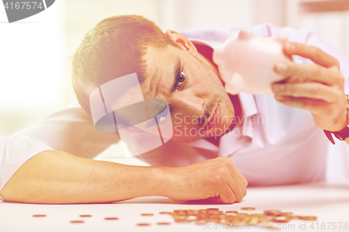 Image of businessman with piggy bank and coins at office