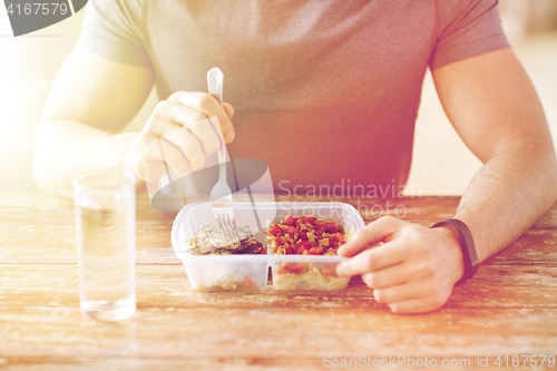 Image of close up of man with fork and water eating food