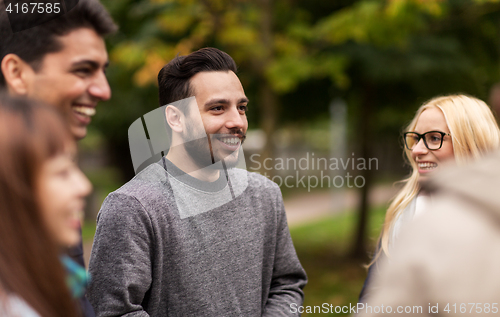 Image of happy friends walking along autumn park