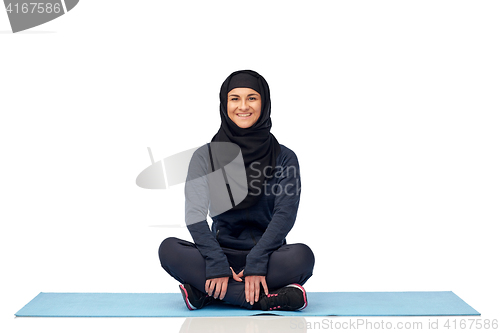 Image of muslim woman doing sport on mat