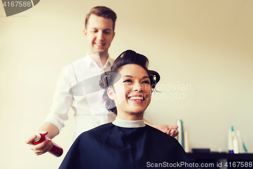 Image of happy woman with stylist making hairdo at salon