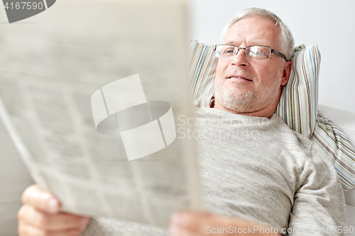 Image of close up of senior man reading newspaper at home