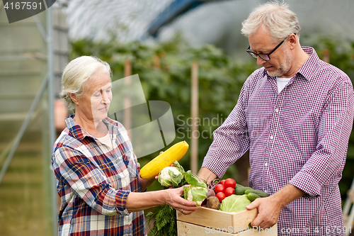 Image of senior couple with box of cucumbers on farm