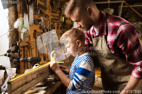 Image of father and son with ruler measure wood at workshop