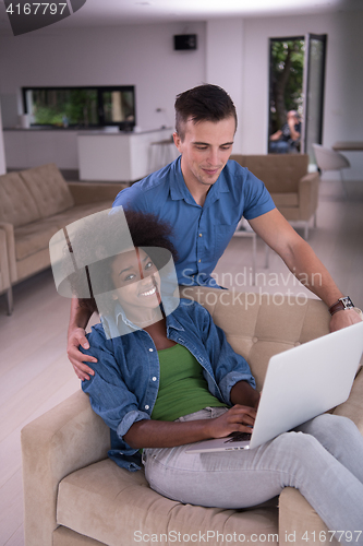 Image of multiethnic couple on an armchair with a laptop