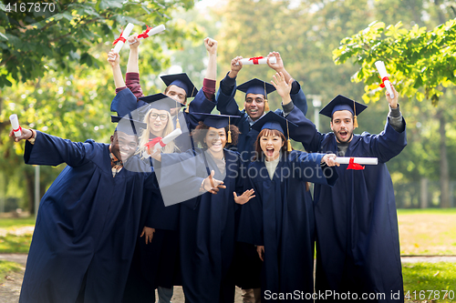 Image of happy students in mortar boards with diplomas