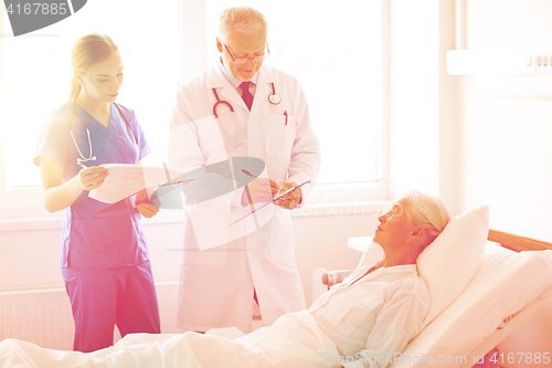 Image of doctor and nurse visiting senior woman at hospital