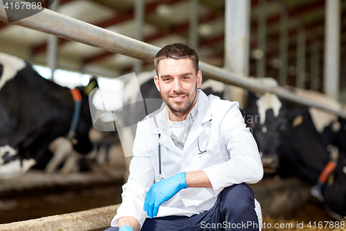 Image of veterinarian and cows in cowshed on dairy farm