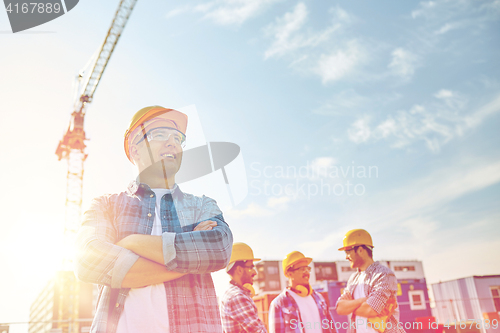 Image of group of smiling builders in hardhats outdoors