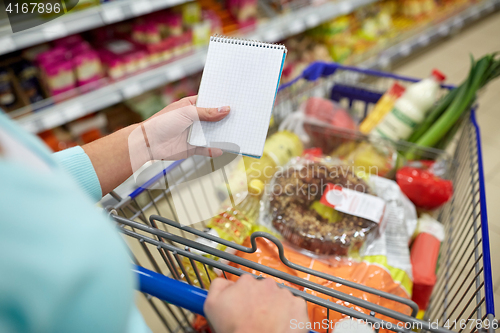 Image of woman with food in shopping cart at supermarket