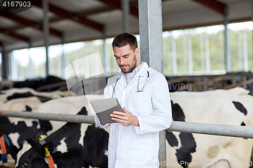 Image of veterinarian with tablet pc and cows on dairy farm