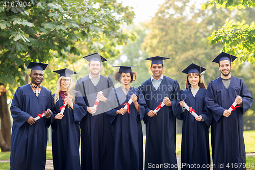 Image of happy students in mortar boards with diplomas