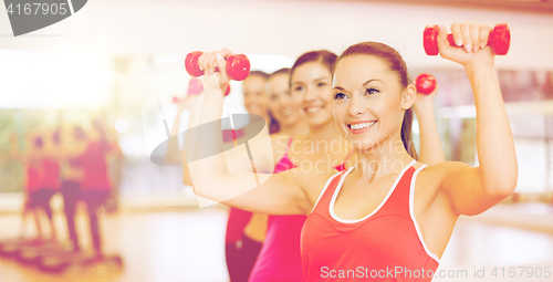 Image of group of smiling people working out with dumbbells