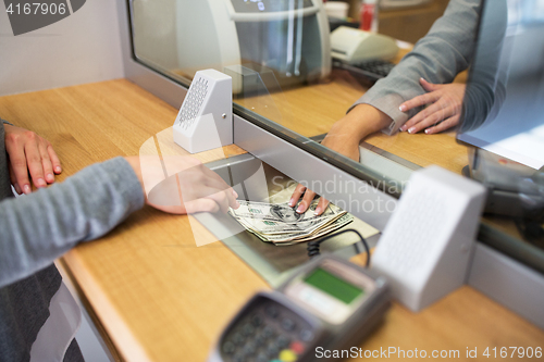 Image of clerk giving cash money to customer at bank office