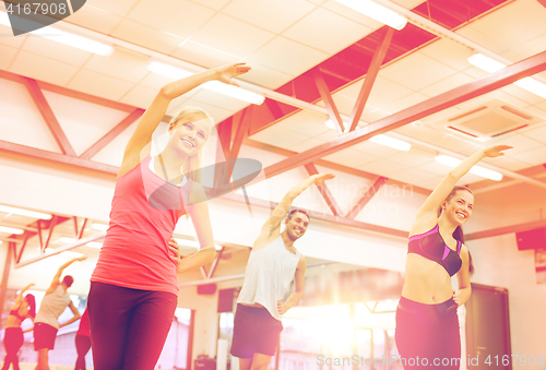 Image of group of smiling people stretching in the gym