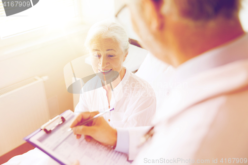 Image of senior woman and doctor with clipboard at hospital