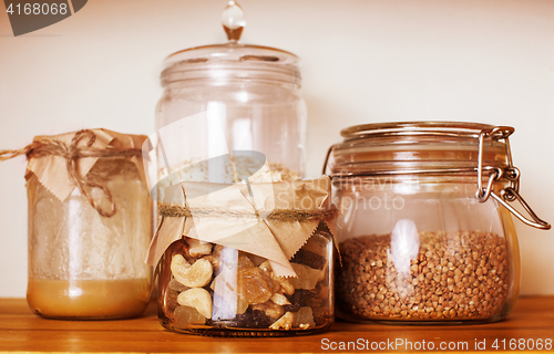Image of real comfort wooden kitchen with breakfast ingredients close up in glass, honey, oatmeal, milk, muesli