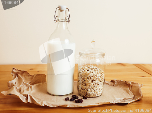 Image of real comfort wooden kitchen with breakfast ingredients close up in glass, honey, oatmeal, milk, muesli