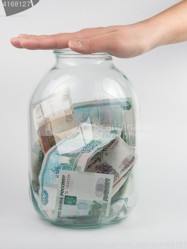 Image of Hand covered the three-liter jar with Russian money
