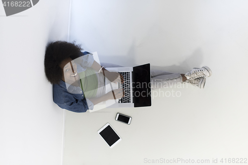 Image of african american woman sitting on floor with laptop top view